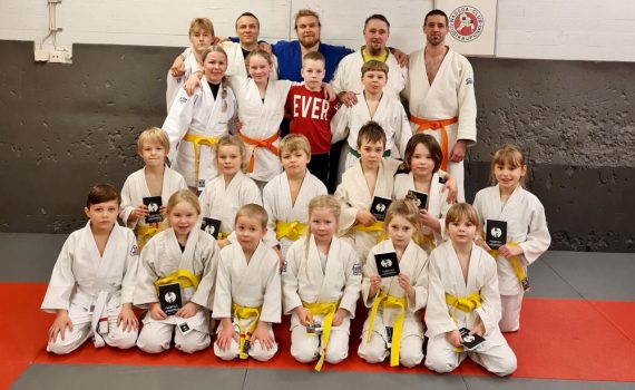 Judokerholaiset ohjaajineen ryhmäkuvassa onnistuneen vyökokeen jälkeen.